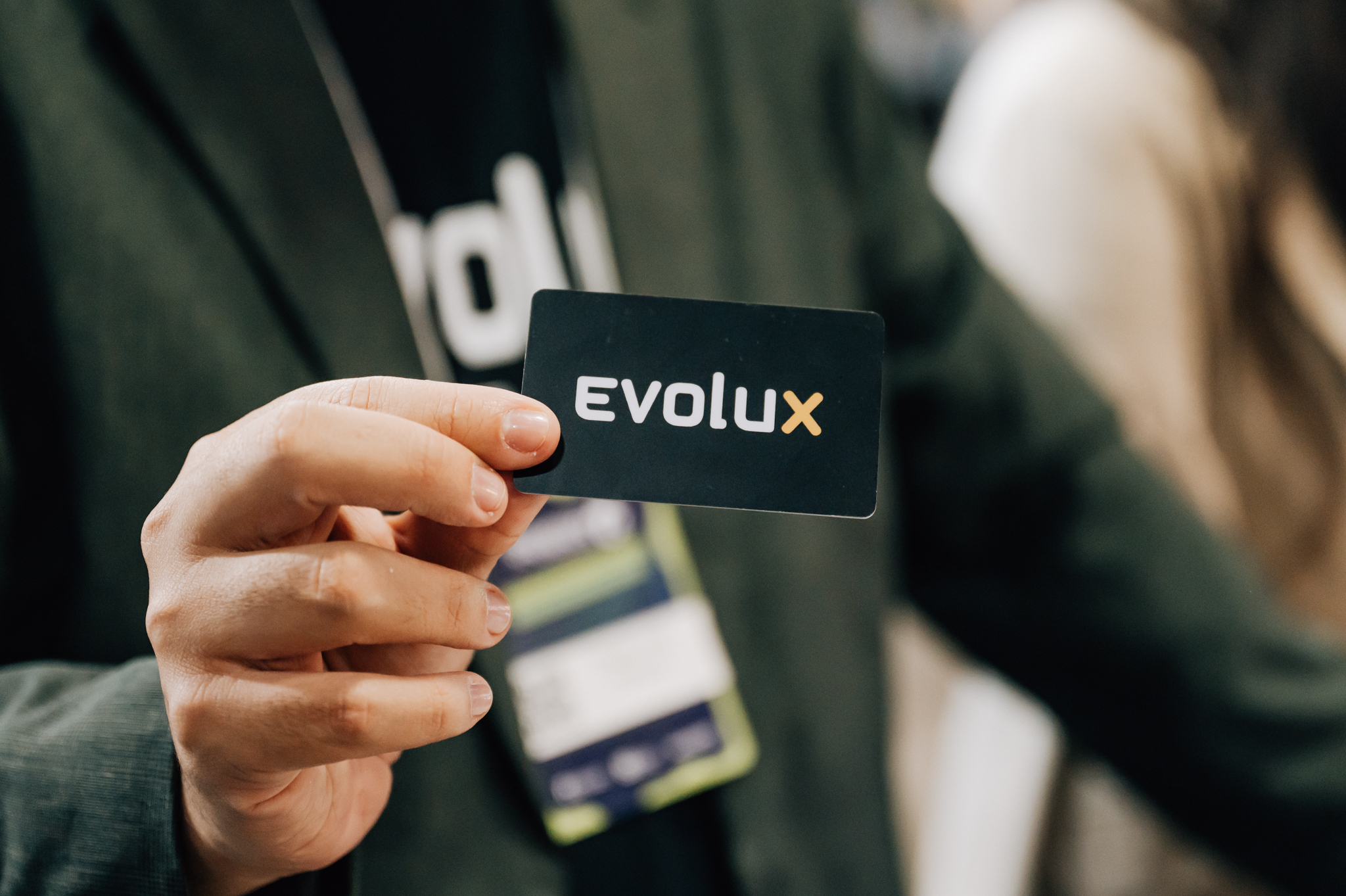 mão de uma pessoa branca segurando um cartão de visita com a marca da empresa Evolux para divulgar a nossa plataforma omnichannel